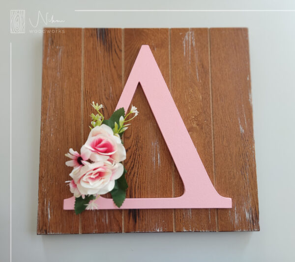 Διακοσμητικό καδράκι με μονόγραμμα, στολισμένο με λουλούδια.